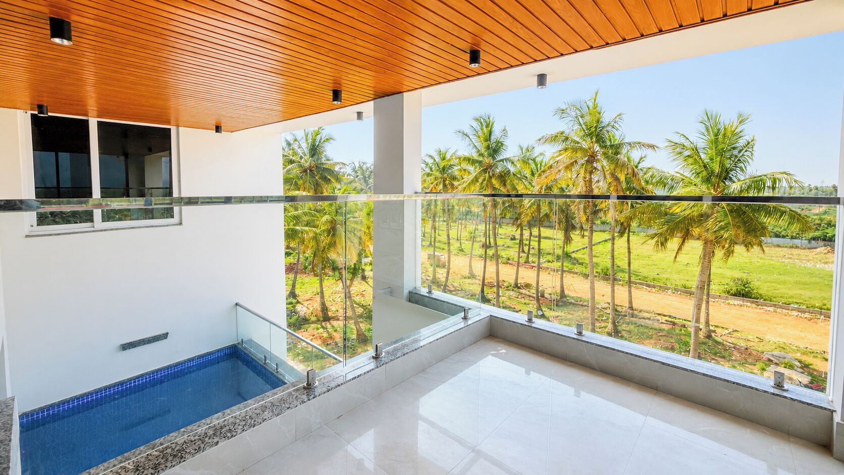 A modern interior with a pool, large windows, and a view of palm trees.