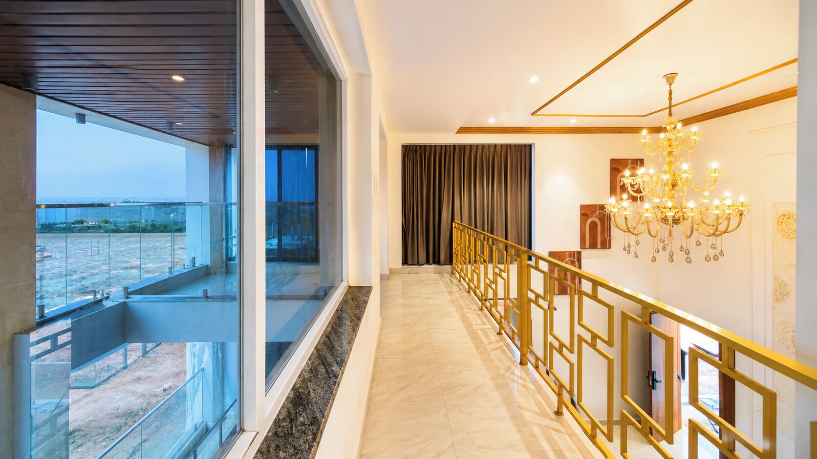 A modern interior with a marble floor, a golden railing, and a chandelier.