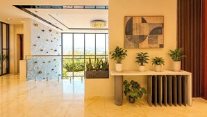 Een moderne lobby met een klimmuur, potplanten en een groot abstract schilderij.