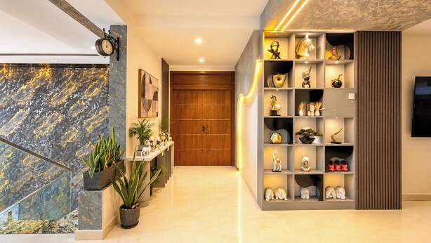 Een modern interieur met een marmeren wand, een houten deur en een plank met decoratieve objecten.