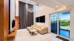 Een moderne woonkamer met een bank, twee salontafels, een televisie en een balkon met uitzicht.
