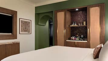 A hotel room with a bed, a wardrobe, a framed picture, and a shelf with toiletries.