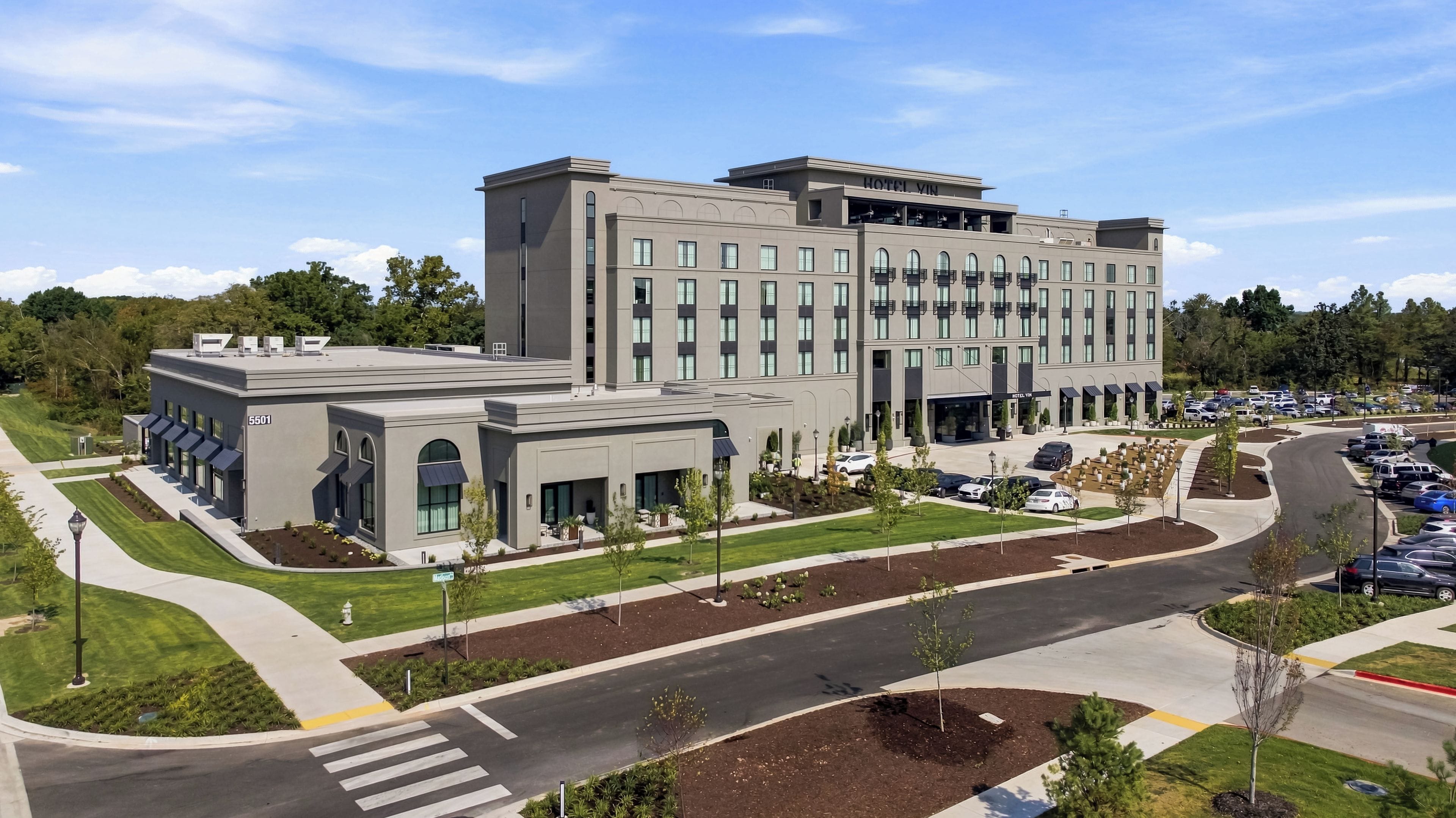 A modern hotel with a central courtyard, multiple parking spaces, and a well-maintained landscape.