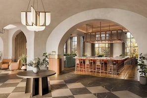 A spacious lobby with a bar area, arched ceilings, and a checkered floor.