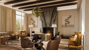 Una sala de estar moderna con sofás de cuero, chimenea y candelabro.