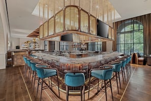 A spacious bar area with a high ceiling and a large TV screen.