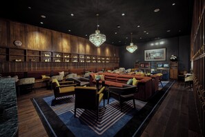 A modern lounge area with a central seating arrangement, wooden paneling on the walls, and a chandelier. - Hotel Vin, Rogers-Bentonville, Autograph Collection (Rogers)