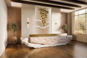 A reception desk with a marble top, a wall-mounted gold decorative piece, and two potted plants.
