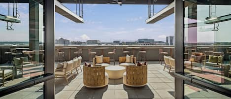 A rooftop lounge with outdoor seating and a city view.