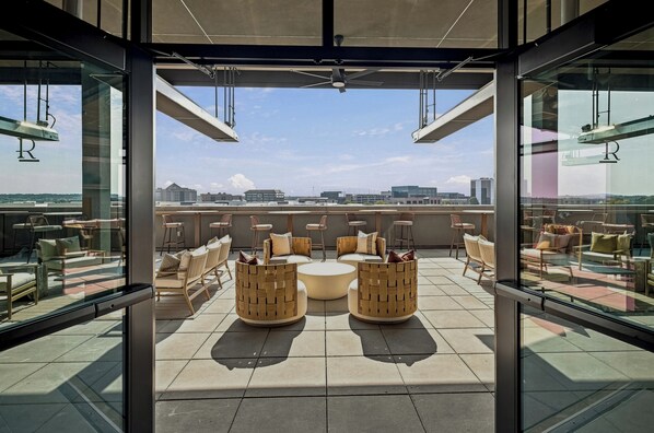 A rooftop lounge with outdoor seating and a city view.