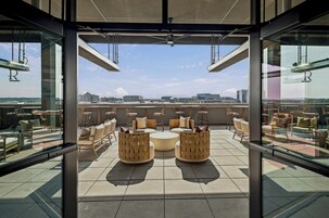 Un salón en la azotea con asientos exteriores y vistas a la ciudad.