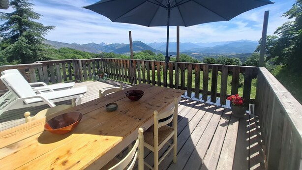 Une terrasse en bois avec une table, des chaises et un parasol.