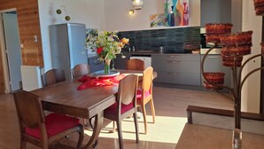 Une cuisine moderne avec des meubles en bois, une table à manger avec des chaises et un vase de fleurs.