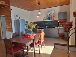 Eine moderne Küche mit Holzausstattung, einem Esstisch mit Stühlen und einer Blumenvase.