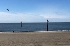 A beach with a clear sky, calm sea, and two tall structures in the water. - Düsseldorfer Hof A1 - first class living (Norderney)