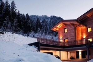 Eine Holzhütte mit einem Balkon, umgeben von schneebedeckten Bäumen.