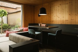 Eine moderne Küche mit Holzwänden, einer Bar und einer Sitzecke mit Sofa und Sesseln.