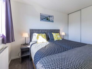 Ein Schlafzimmer mit einem Bett, zwei Nachttischen, einem Fenster mit Vorhängen und einem Wandbild.