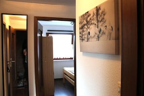 Ein Flur mit einem Bett, einer Tür und einem Wandbild.