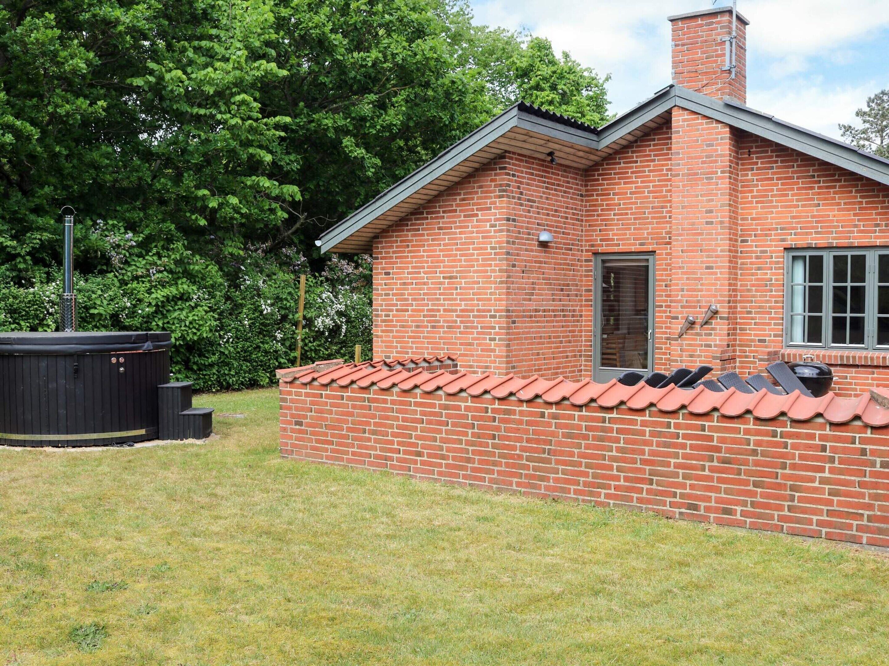 A brick house with a tiled roof, a hot tub, and a grill area.
