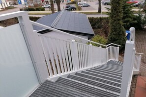 Eine weiße Metalltreppe mit Geländer, die zu einem Hauseingang führt.