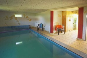A swimming pool with a tiled deck, a chair, and a red pillar. - Holiday home in Priborn with swimming pool (Priborn)