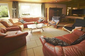 A living room with leather sofas, a coffee table, and a television. - Holiday home in Priborn with swimming pool (Priborn)