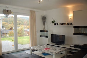 Ein modernes Wohnzimmer mit Fernseher, Sofa und einem Tisch mit Dekoration.