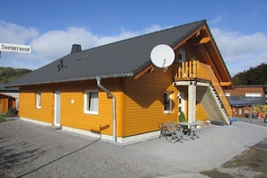 Ein Holzgebäude mit Satellitenschüssel, Treppe und einem Schild, auf dem 'Seetrasse' steht.