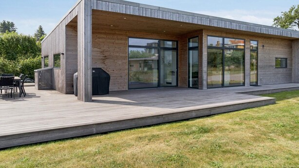 A modern house with a covered patio, large glass doors, and a wooden deck. - 4 Star Holiday Home in Allinge (Allinge)