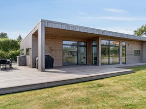 A modern house with a covered patio, large glass doors, and a wooden deck. - 4 Star Holiday Home in Allinge (Allinge)