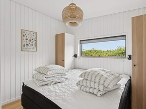 A bedroom with a bed, a window with a view, a hanging light fixture, and a framed picture on the wall. - 4 Star Holiday Home in Allinge (Allinge)