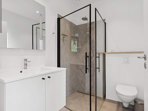 A modern bathroom with a glass shower enclosure, a white sink, and a toilet. - 4 Star Holiday Home in Allinge (Allinge)