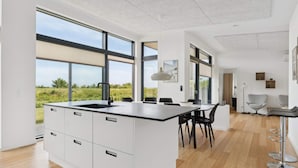 A modern kitchen with a large island, white cabinetry, and a view of the outdoors. - 4 Star Holiday Home in Allinge (Allinge)