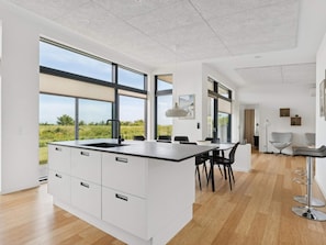 Una cocina moderna con una isla grande, armarios blancos y vistas al exterior.