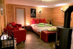 Une pièce confortable avec un lit, des fauteuils rouges, une table, un radiateur et un tableau accroché au mur.