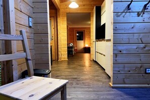 Ein Holzboden-Flur mit einer Sitzbank, einer Tür und einer Wandleuchte.