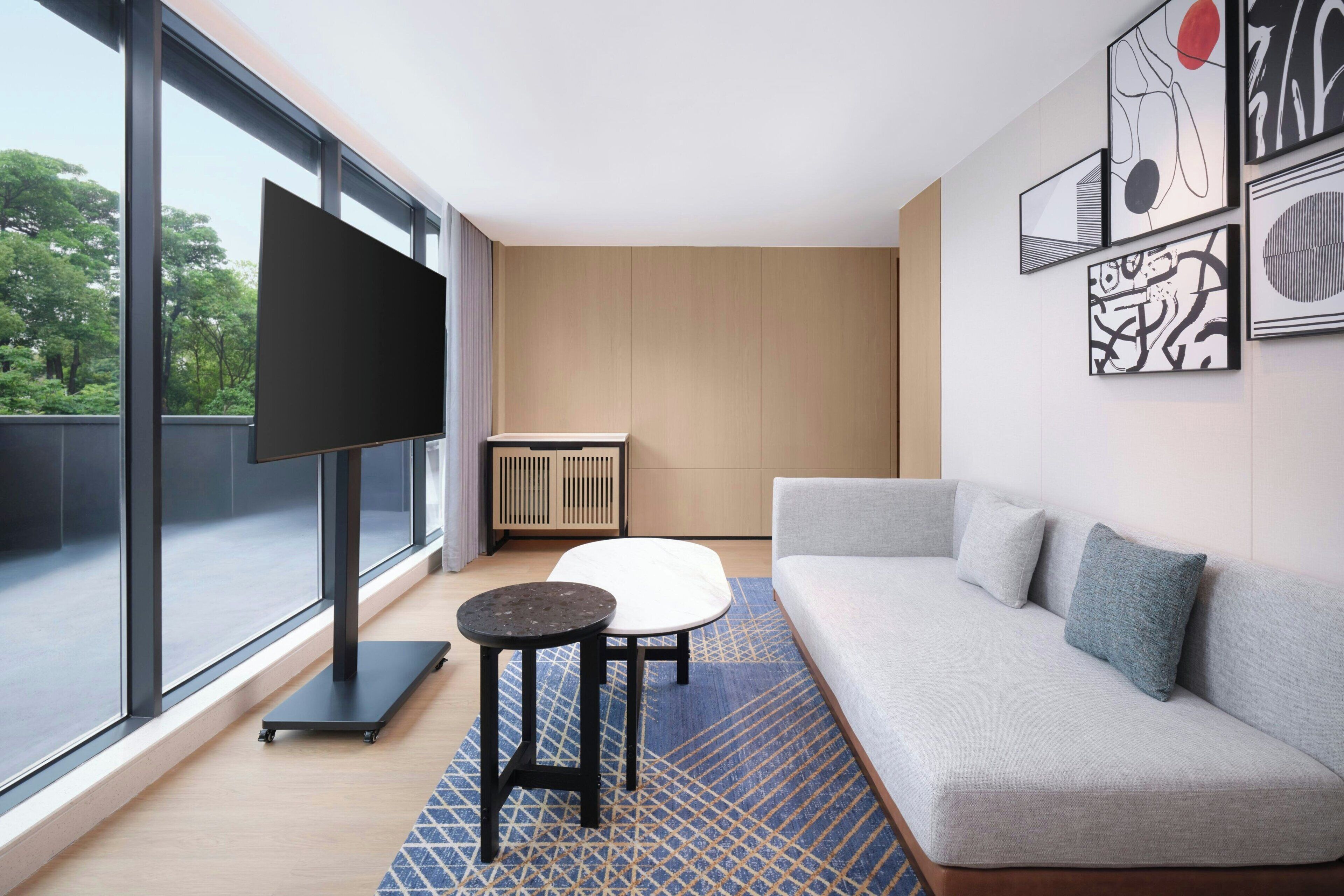 Ein modernes Wohnzimmer mit einer Couch, einem Couchtisch, einem Fernseher auf einem Schrank und Kunstwerken an der Wand.