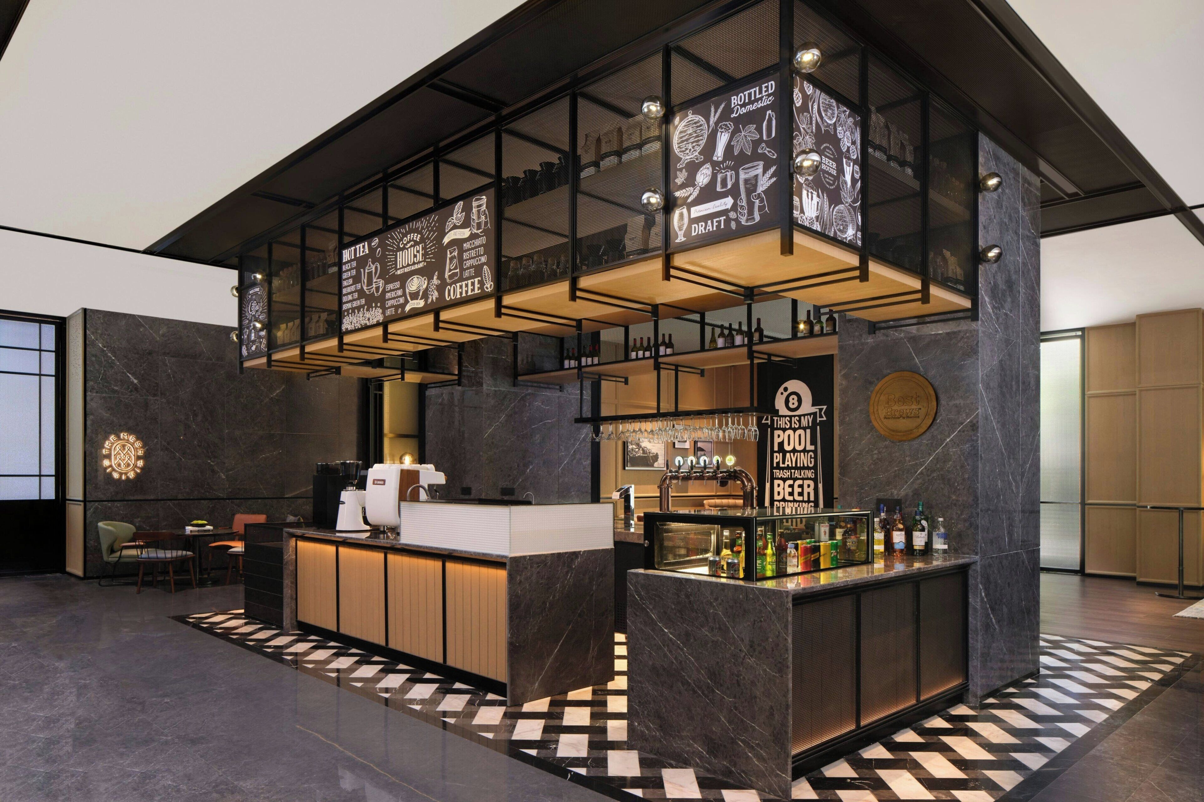 A modern bar area with a coffee station, a selection of bottles, and a sign indicating draft beer.