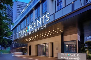 Exterior de hotel com uma placa de destaque com a inscrição 'FOUR POINTS BY SHERATON' e uma série de luzes ao longo da entrada.