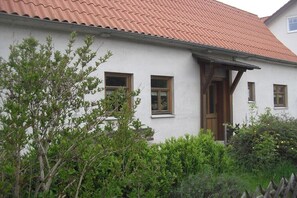 Ein weißes Gebäude mit rotem Dach, Holzfenstern und einer Tür.