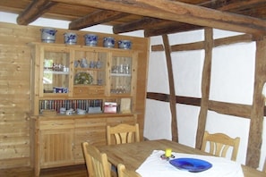 A wooden dining table with chairs, a cabinet with glass doors, and a wooden ceiling structure. - Holiday home in Rhön with 2 bedrooms (Gersfeld OT Sparbrod)