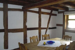 A dining area with a wooden table and chairs, a white tablecloth, and a window with natural light. - Holiday home in Rhön with 2 bedrooms (Gersfeld OT Sparbrod)