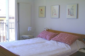 Ein Schlafzimmer mit einem Bett, zwei Kissen, einem Sessel und drei Wandbildern.