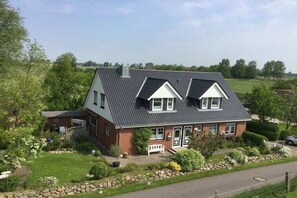 A two-story house with a sloped roof, a front porch, and a stone pathway leading to the entrance. - Holiday apartment with 2 bedrooms (Tönning)