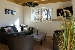 A living room with a sofa, a coffee table, and a TV on the wall. - Holiday home Sonnenufer (Dorf Zechlin  Ortsteil Beckersmühle)