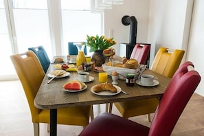 A breakfast table with various food items, a coffee pot, and a vase with flowers. - Holiday home Sonnenufer (Dorf Zechlin  Ortsteil Beckersmühle)