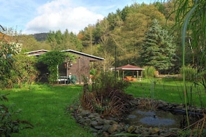 Eine rustikale Holzhütte mit einem kleinen Teich, umgeben von üppigem Grün und Bäumen.