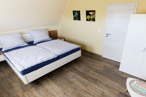 A bedroom with a bed, wooden flooring, a wardrobe, and two wall-mounted pictures. - 2 Zeitke "the Little One" (Altefähr)