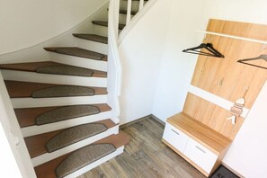A staircase with wooden steps and carpeted risers, a white wall, and a wooden shelf with hangers. - 2 Zeitke "the Little One" (Altefähr)